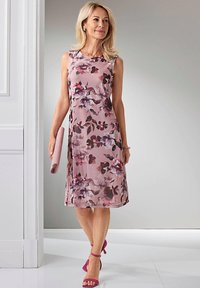 Blumen-Midi-Kleid in sanftem Rosa mit dunkellila und kastanienbraunen Akzenten, ärmelloses Design, glattes Material. Eine Clutch und pinke High Heels ergänzen den Look.