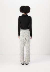 Black ribbed long-sleeve top paired with light gray fuzzy patterned pants, featuring a wide waistband and tapered legs, viewed from the back.