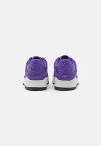 Lilla sneakers med en tekstureret overdel, broderede detaljer og en hvid mellemsål. Sort gummisål. Bagfra ses karakterdesignet.