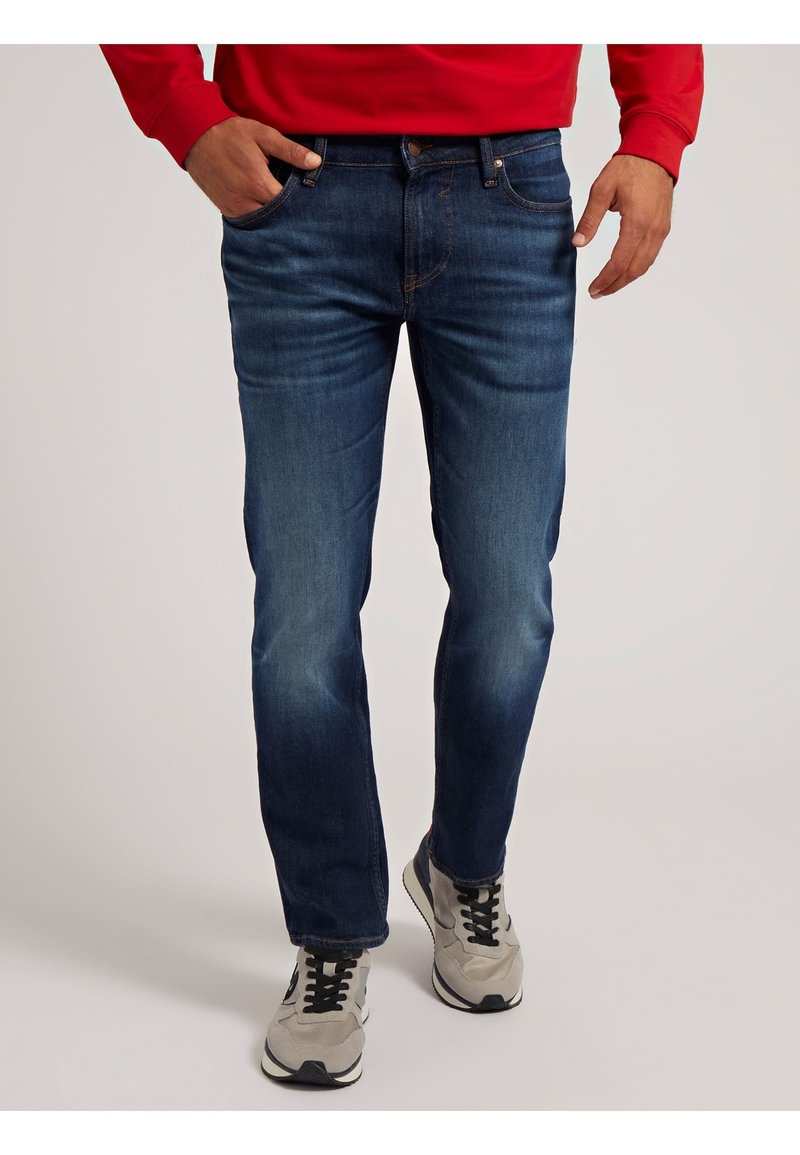 Jeans en denim bleu marine avec une coupe droite, présentant un design classique à cinq poches, un léger délavage et des coutures contrastantes.