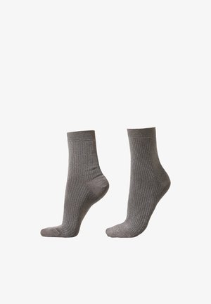 Chaussettes grises côtelées avec une texture douce, présentant un design mi-mollet et des poignets élastiqués pour un ajustement parfait.