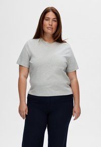 Camiseta de algodón gris con mangas cortas y escote redondo, combinada con pantalones azul marino. Diseño simple, sin patrones o acentos visibles.