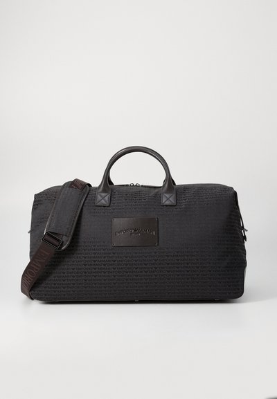 Sort duffel bag med tekstureret stof, læderhåndtag og en aftagelig rem. Har et præg af logopatch og lynlås lukning.