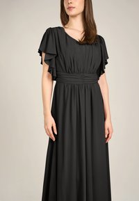 Schwarzes Maxikleid mit Rüschenshortsärmeln, gefaltetem Oberteil und gerafftem Taillenbereich. Hergestellt aus glattem, fließendem Stoff.