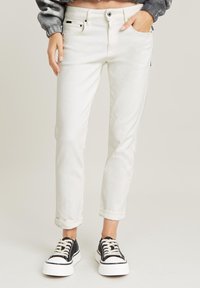 Vita avkortade jeans med slim fit, med en klassisk femfickorsdesign och uppvikta muddar. I kombination med svarta och vita plattformsskor.