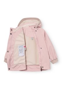 Otroški roza vetrovki s kapuco, obloženi z bež flisom, z rebrastimi manšetami in ovratnikom, delno odprta z zadrgo, da se pokaže notranja etiketa.