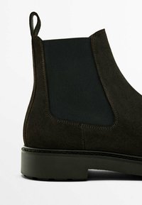 Ciemnozielone zamszowe botki za kostkę z elastycznym panelem bocznym i kontrastującym czarnym tekstylnym wykończeniem. Posiadają solidną podeszwę i wzmocnione detale szwów.