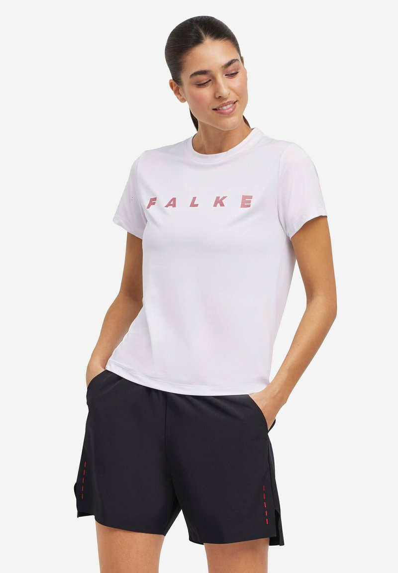 T-shirt FALKE blanche à manches courtes et col rond, associée à un short noir avec des coutures rouges en accent et des poches latérales.