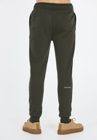 Groene katoenen sweatpants met elastische tailleband, zijzakken en witte tekst "LES' ARCS". Zachte structuur met een taps toelopend ontwerp.