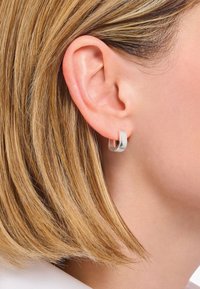 Orecchino a cerchio in argento con design arrotondato e chiuso. Finitura lucida con superficie liscia, con un diametro di circa 1 pollice.