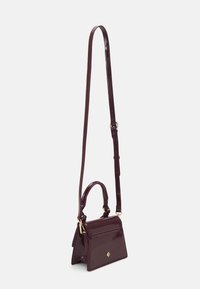 Burgundy patent leather handbag with a structured design, adjustable shoulder strap, top handle, and gold hardware. Features a diamond accent.