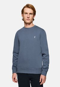 Blå sweatshirt i blød bomuldsblanding, rund hals, ribbede manchetter og nederste kant, med et lille hvidt logo på brystet. Enkel, afslappet pasform.
