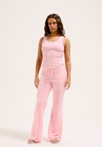Top rosa con pizzo e dettagli di strass, abbinato a pantaloni a zampa coordinati con vita elastica e cordino.