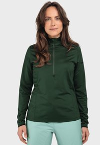 Grüner Quarter-Zip-Pullover aus feuchtigkeitsableitendem Material, mit langen Ärmeln und schmaler Passform. Logo-Detail am Ärmel. Glatte Textur.