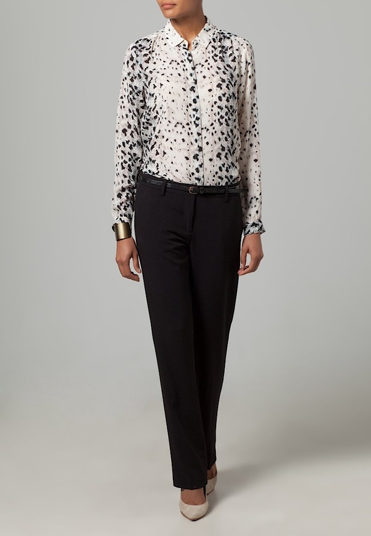 Kevyt, läpikuultava pusero, jossa mustavalkoinen täplikkäät kuvio, kaulus, napitettu, yhdistetty mustiin housuihin ja korkokenkiin.