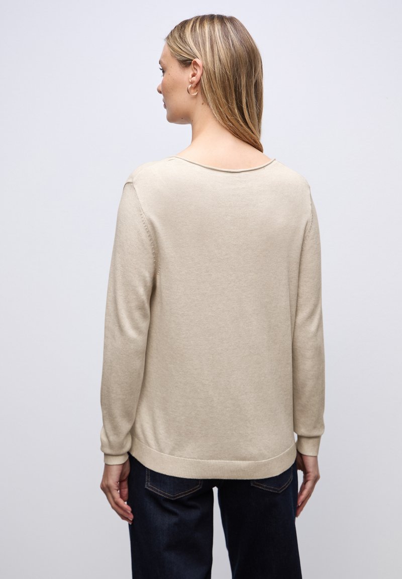 Beige pletený svetr s uvolněným stříháním, kulatým výstřihem a dlouhými rukávy. Textura je jemná a design obsahuje žebrované manžety a spodní lem.