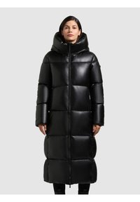 Lungo cappotto imbottito nero con colletto alto, grande cappuccio e sezioni trapuntate per l'isolamento. Materiale liscio e lucido, design fino al ginocchio.