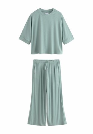 Lichtgroene losse top met korte mouwen en ronde hals en bijpassende wijde broek met trekkoord, beide gemaakt van zachte, vloeiende stof.