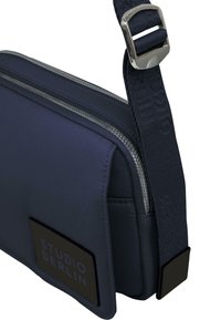 Borsa a tracolla della marina realizzata in nylon, con cerniere argentate, una texture imbottita, una tracolla regolabile e una patch logo nera.