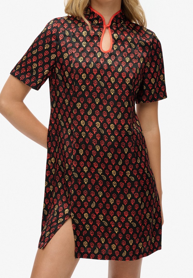 Robe à manches courtes en tissu noir avec un motif floral rouge et or, un col montant et une ouverture en forme de trou de serrure à l'avant avec des fentes latérales.