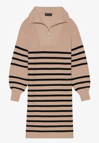 Robe en maille beige avec un col à zip quart, présentant des rayures horizontales noires et une texture côtelée sur le corps et les manches.