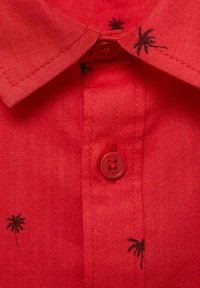 Röd linneskjorta med krage som går att knäppa, svart palmträdbroderi och en matchande röd knapp vid kragen.
