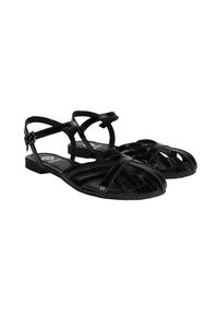 Schwarze Sandalen mit Riemchen und flacher Sohle, die über ausgeschnittene Muster und eine glänzende Textur verfügen. Verstellbarer Knöchelriemen für einen sicheren Halt.