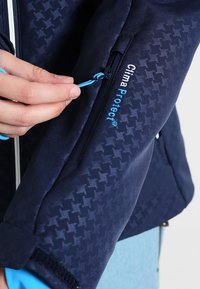 Marineblaue Jacke mit strukturiertem Muster, seitlicher Reißverschluss-Taschen mit blauen Ziehband und "Clima Protect"-Logo. Glattes Material mit tailliertem Design.