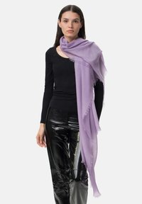 Lys lilla tørklæde med et blødt, textured stof, der har flagrende kanter, draperet afslappet over skuldrene på en person iført en sort top.