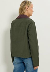 Oliven grøn jakke med en ribbet bordeaux krave, lige snit, lange ærmer og en glat tekstur. Bagfra visning, afslappet design.