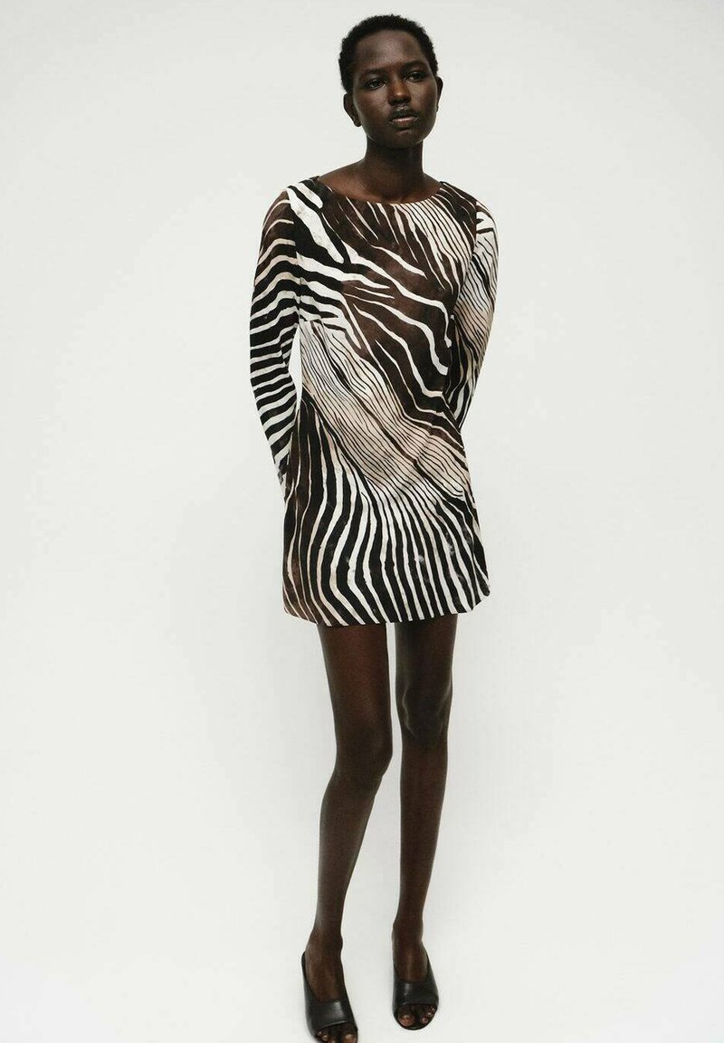 Zebra-gemist kleed met een losse pasvorm, lange mouwen en een asymmetrische halslijn. Gemaakt van een lichte, doorschijnende stof in bruin en crèmekleuren.