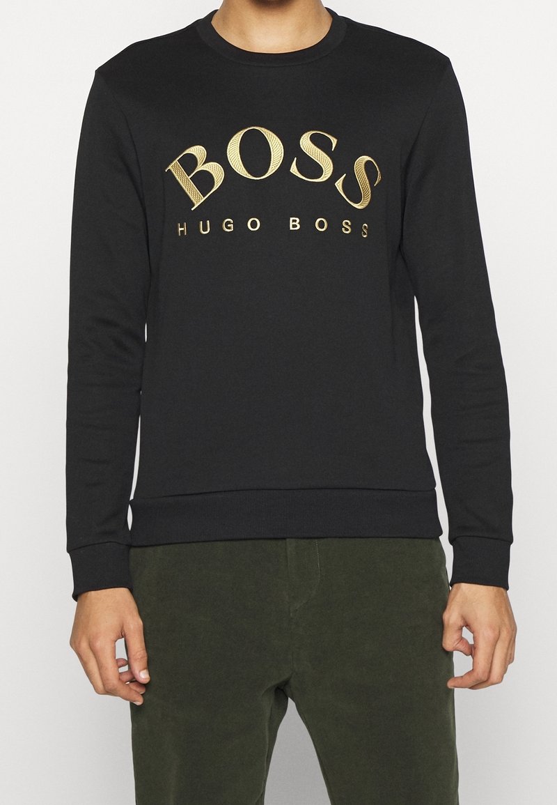 Felpa nera con maniche lunghe, scollo rotondo e logo dorato "BOSS HUGO BOSS" ben visibile sul petto. Tessuto morbido in misto cotone.