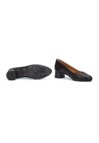 Chaussures en cuir noir avec un bout arrondi, un design supérieur perforé et un petit talon en bloc. Semelle en caoutchouc texturée avec un motif.