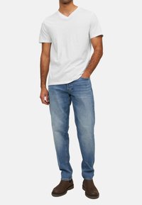 Hvid v-hals t-shirt, blå jeans, brune ankelstøvler. Casual pasform med lige ben, lysvasket denim, minimalistisk design.