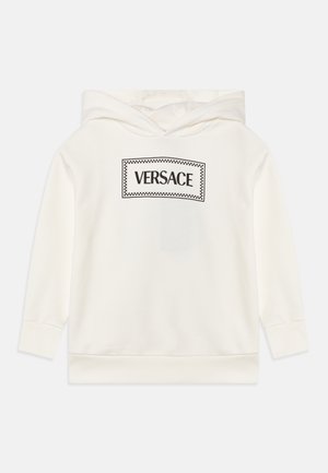 Biela mikina vyrobená z jemného materiálu s čierne vyšitým logom "VERSACE" v obdélnikovom dizajne s kockovaným okrajom.
