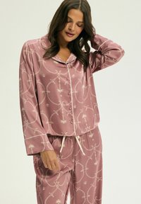 Różowy satynowy zestaw piżamowy z kwiatowym i geometrycznym wzorem, długimi rękawami, koszulą zapinaną na guziki oraz spodniami z elastycznym pasem i sznurkiem.