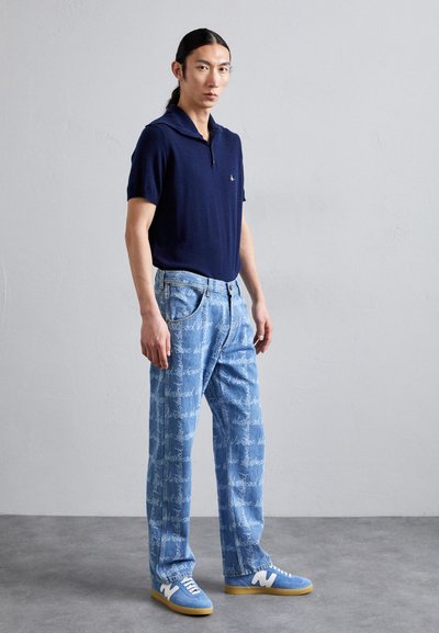 Navy polo shirt with a collar, light blue denim jeans featuring a white text print, and blue sneakers with white accents.
