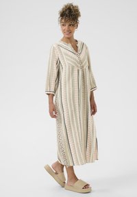 Robe longue rayée aux couleurs pastel avec des motifs géométriques, devant boutonné et fentes sur les côtés. Portez-la avec des sandales à enfiler en osier.
