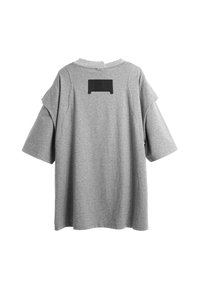 Camiseta gris de gran tamaño con mangas cortas, cuello redondo y un acento rectangular negro en la parte posterior. Hecha de una tela suave y texturizada.
