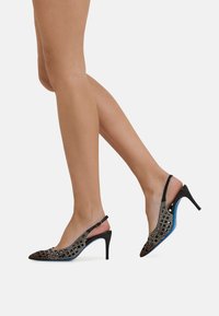 Scarpe col tacco alto nere slingback con tomaia in rete testurizzata, caratterizzata da un motivo geometrico e un accento blu sulla suola.