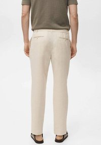 Beige linnen broek met een recht gesneden ontwerp, voorzien van achterzakken en een zachte textuur. Gestoeld met donkere schoenen.