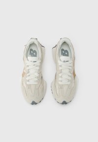 Tenisky s béžovým semišovým zvrškom, bielymi šnúrkami a sivými akcentmi. Navrhnuté s textúrovanou podrážkou a logom na stielke.