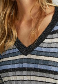 Gestrickter V-Ausschnitt-Pullover mit horizontalen Streifen in Hellblau, Grau, Schwarz und Weiß, versehen mit einem strukturierten Muster und metallischen Fäden.