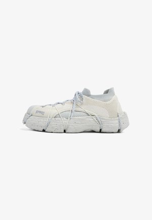 Off-white strikket sneakers med en kraftig segmenteret sål, omsluttende snørebånd og sok-lignende ankelskaft, set fra siden.