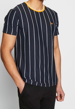 Man wearing navy blue short-sleeve t-shirt with vertical white stripes and orange trim at round neck, paired with black pants.