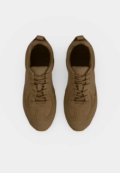 Paire de baskets en daim marron à lacets vues de dessus sur fond blanc.