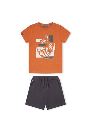 Camiseta naranja de manga corta con gráfico fragmentado blanco de león y texto "Jungle in Wild", combinada con pantalones cortos gris oscuro con cordón.