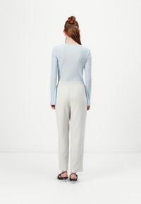 Haut à manches longues côtelé bleu clair associé à un pantalon gris clair avec taille élastique, porté avec des sandales à talons noires. Design simple et élégant.
