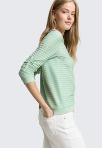 Lichtmintgroene sweatshirt met getextureerde, horizontale strepen. Voorzien van aansluitende manchetten en een comfortabele pasvorm. Gecombineerd met witte broek.