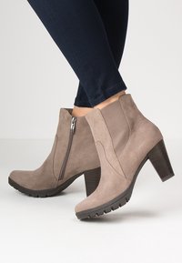 Stivaletti alla caviglia in suede taupe con cerniera laterale, tacco affusolato testurizzato e suola in gomma con battistrada per la presa.